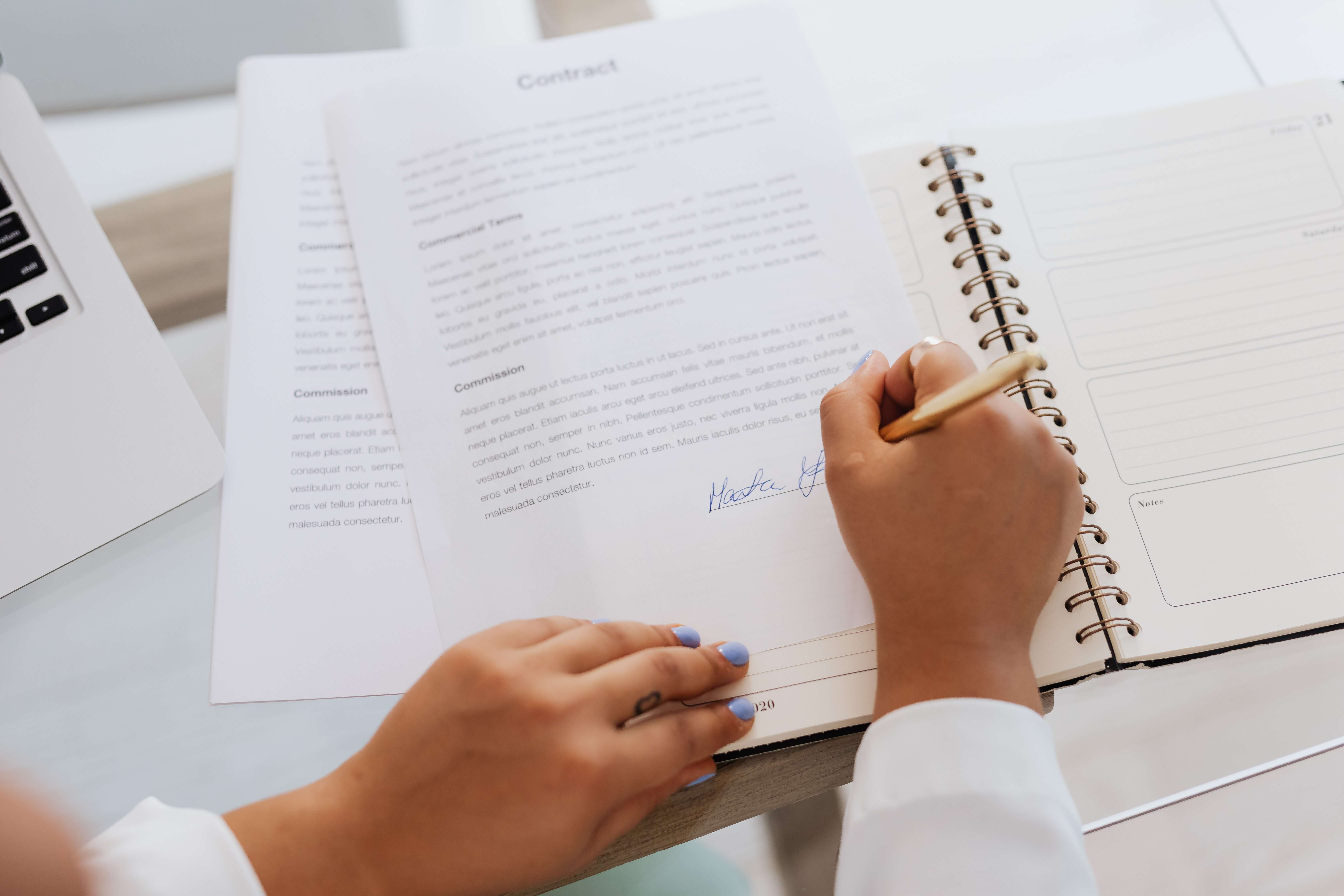 A hand, signing a WordPress maintenance contract.